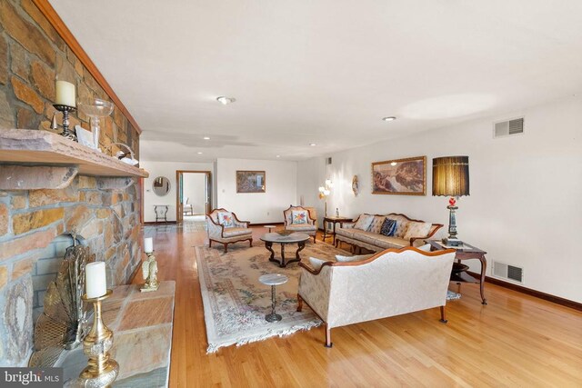 living room with visible vents, a fireplace, baseboards, and wood finished floors