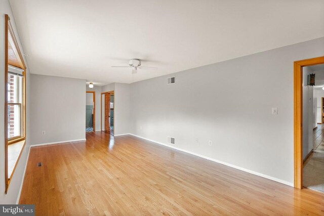 unfurnished room with ceiling fan, visible vents, light wood-style flooring, and baseboards