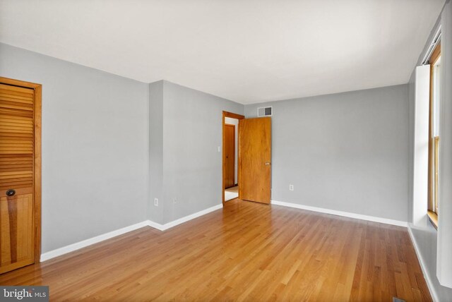 spare room featuring visible vents, baseboards, and wood finished floors