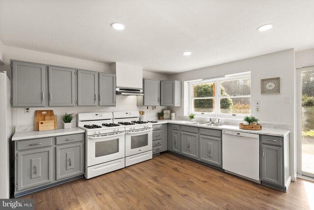 kitchen with dark wood-style flooring, recessed lighting, gray cabinets, white appliances, and under cabinet range hood