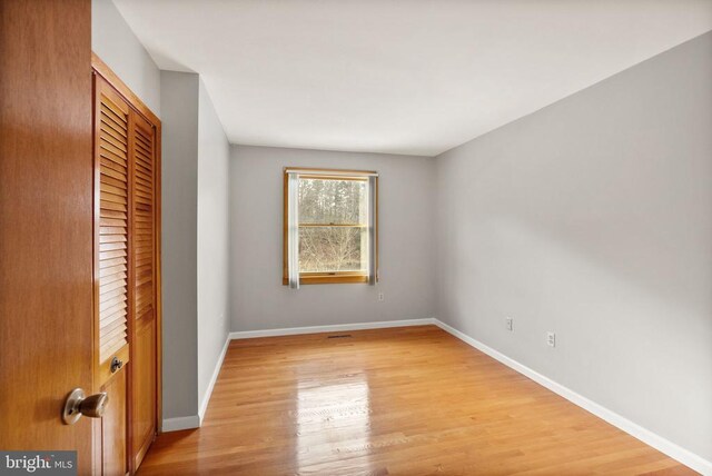 unfurnished bedroom with baseboards, a closet, and light wood-style floors