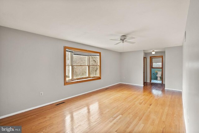 spare room featuring light wood finished floors, baseboards, and visible vents