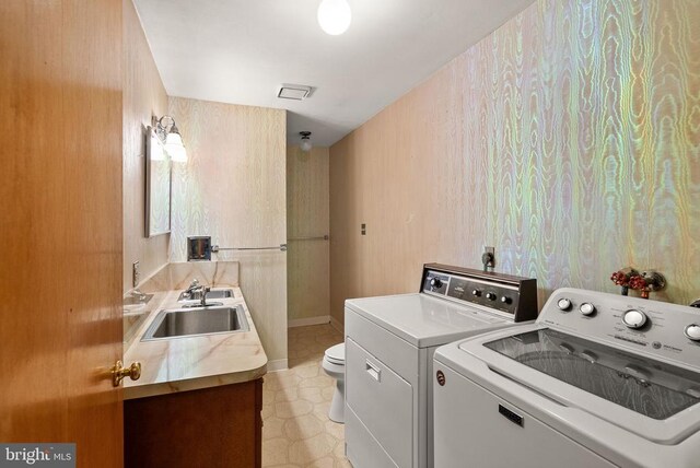 laundry area featuring washing machine and dryer, laundry area, a sink, visible vents, and baseboards