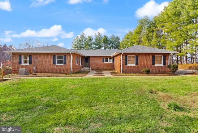 single story home featuring central AC, brick siding, a fire pit, and a front lawn