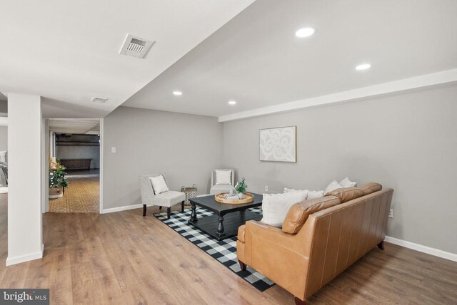 living room featuring baseboards, visible vents, wood finished floors, and recessed lighting