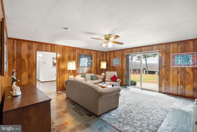 living room with ceiling fan and wood walls