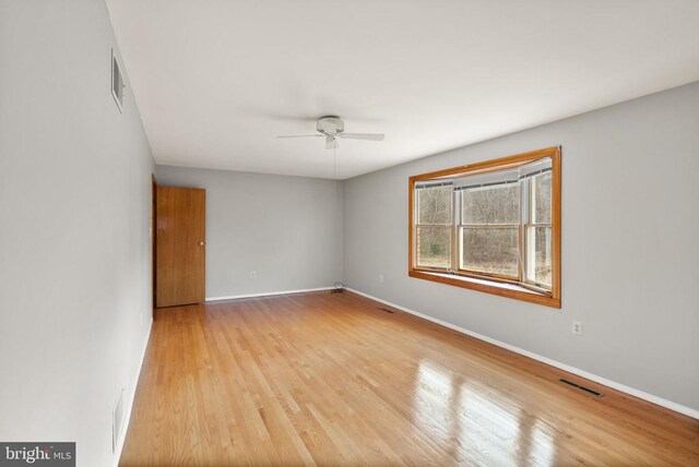 unfurnished room with a ceiling fan, baseboards, visible vents, and wood finished floors