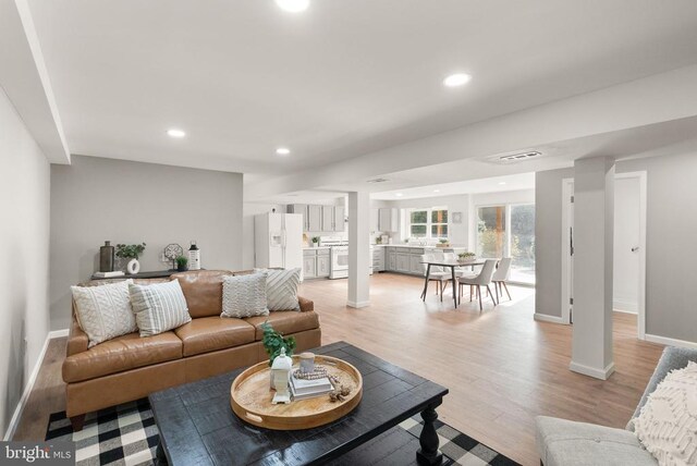 living room featuring recessed lighting, visible vents, decorative columns, and light wood-style flooring