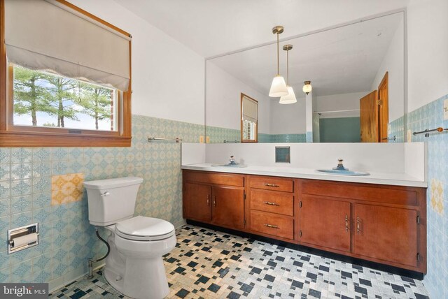 bathroom featuring double vanity, tile walls, a sink, and wainscoting