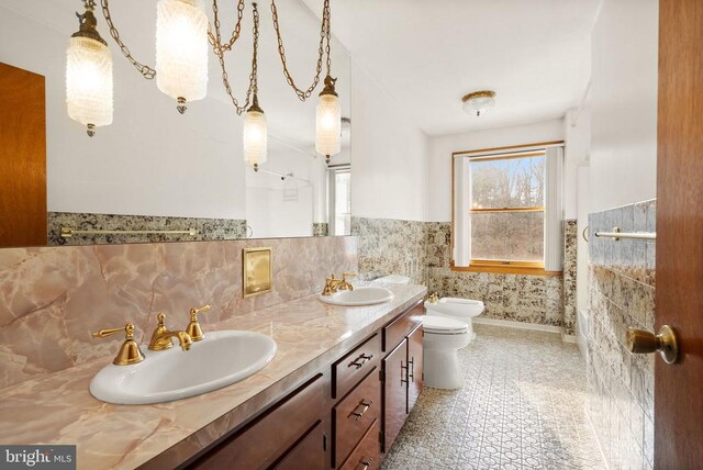 full bathroom featuring toilet, a wainscoted wall, a bidet, and a sink