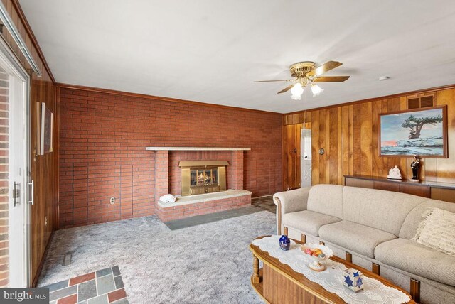 living room featuring brick wall, wood walls, a fireplace, and visible vents