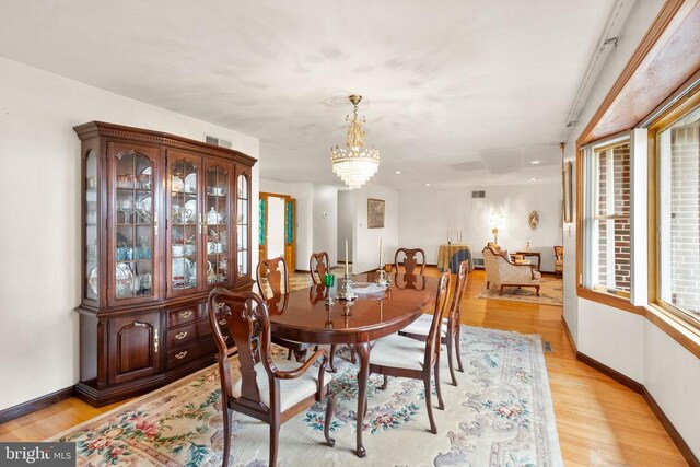 dining area featuring baseboards, light wood finished floors, visible vents, and a notable chandelier