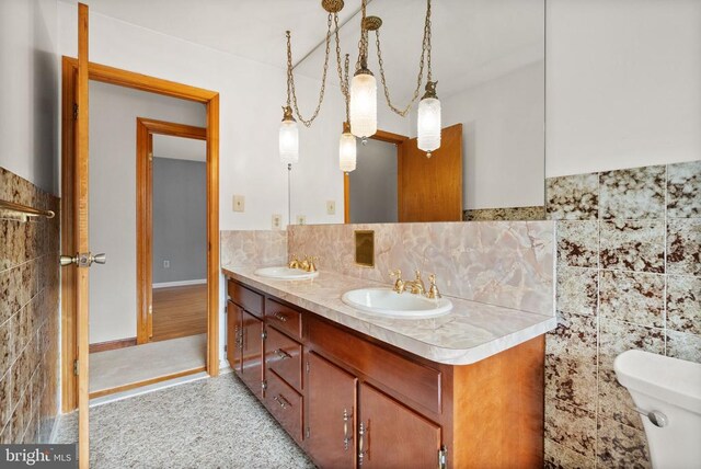 bathroom with double vanity, a sink, and tile walls