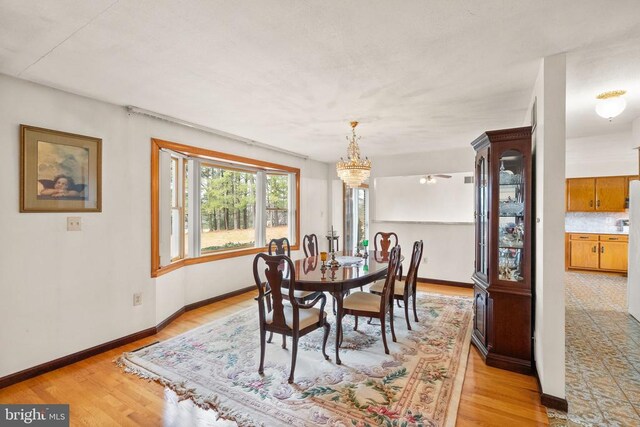 dining space with a chandelier, baseboards, and light wood finished floors