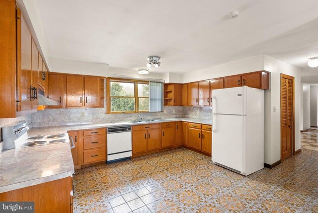 kitchen featuring white appliances, light countertops, backsplash, and under cabinet range hood