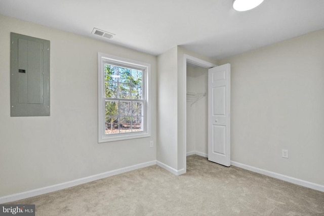 unfurnished bedroom featuring light colored carpet, electric panel, and a closet