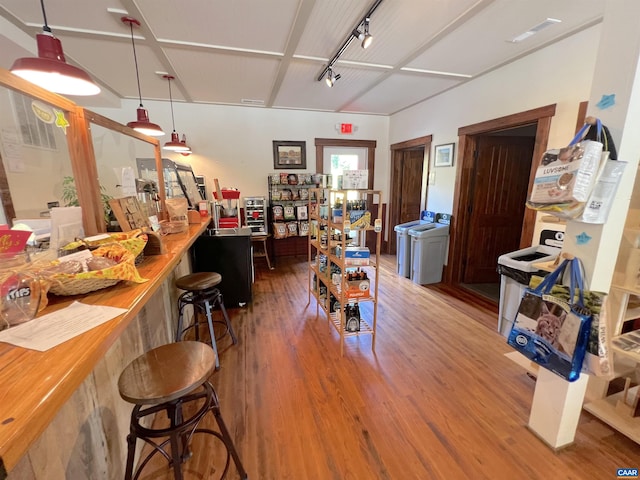 miscellaneous room featuring washing machine and dryer, rail lighting, and hardwood / wood-style floors