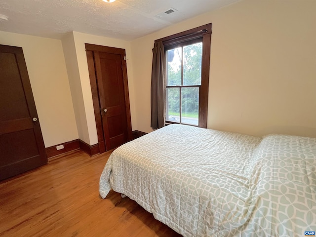 bedroom featuring hardwood / wood-style flooring, a closet, and a textured ceiling