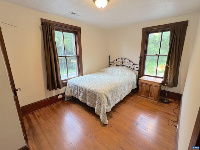 bedroom with multiple windows, hardwood / wood-style flooring, and a textured ceiling