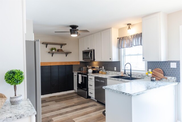 kitchen featuring light stone counters, appliances with stainless steel finishes, sink, and white cabinets