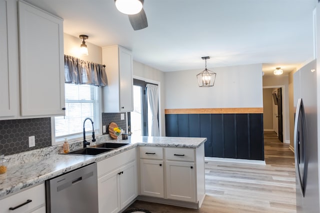 kitchen with appliances with stainless steel finishes, white cabinetry, a sink, and a peninsula