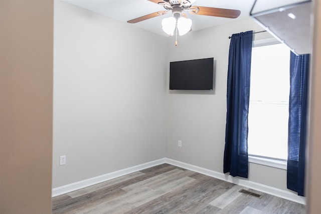 empty room featuring ceiling fan, wood finished floors, visible vents, and baseboards