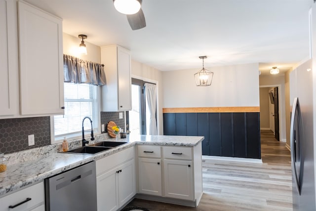 kitchen with appliances with stainless steel finishes, decorative light fixtures, sink, white cabinets, and kitchen peninsula