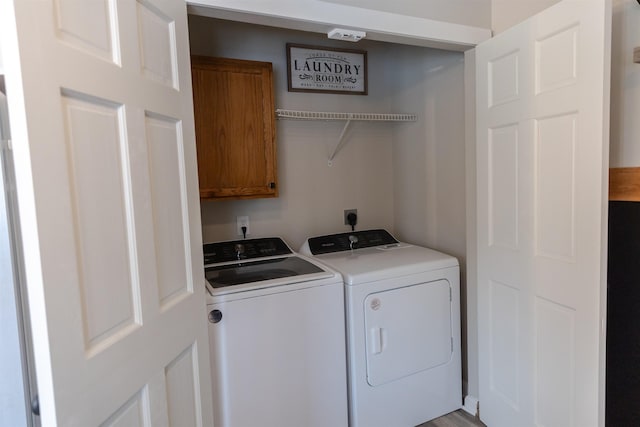 clothes washing area with washing machine and dryer and cabinet space