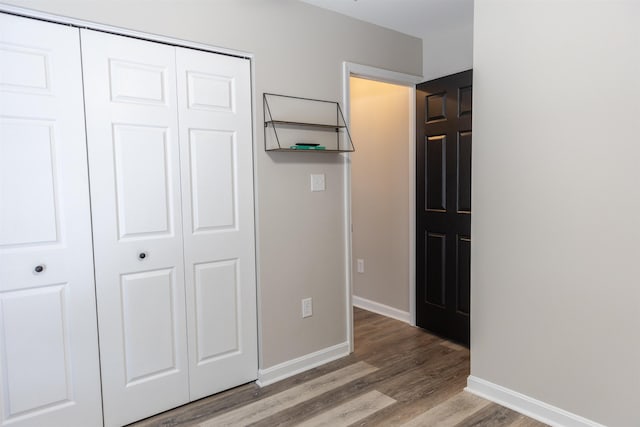 unfurnished bedroom with a closet, baseboards, and wood finished floors