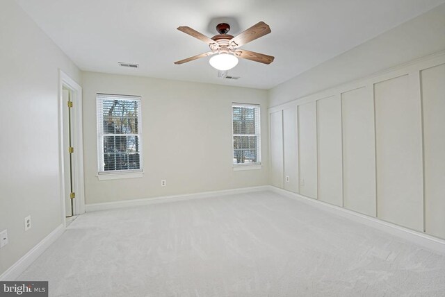 unfurnished bedroom with multiple closets, light colored carpet, and ceiling fan