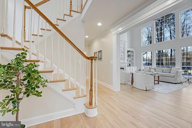 interior space with hardwood / wood-style floors, crown molding, and a towering ceiling