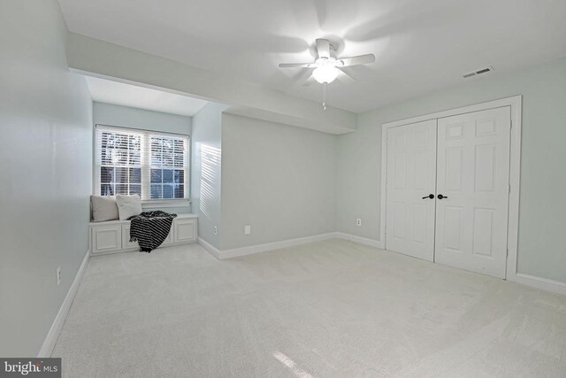 bedroom with light colored carpet, ceiling fan, and a closet