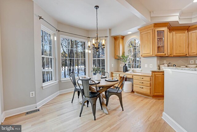 dining space with beamed ceiling, a healthy amount of sunlight, a notable chandelier, and light wood-type flooring