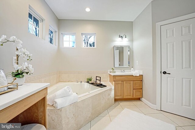 bathroom featuring vanity, tile patterned flooring, and tiled tub