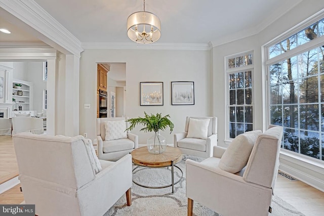 living room featuring a notable chandelier, ornamental molding, and light hardwood / wood-style floors