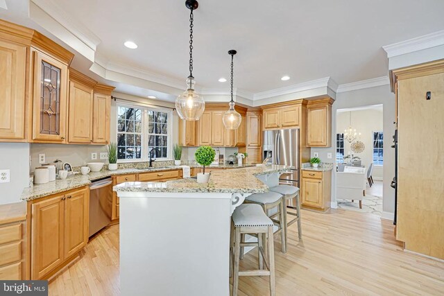 kitchen featuring a kitchen island, pendant lighting, sink, stainless steel appliances, and light stone countertops