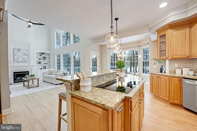 kitchen with hanging light fixtures, a kitchen breakfast bar, black electric stovetop, light hardwood / wood-style floors, and stainless steel dishwasher