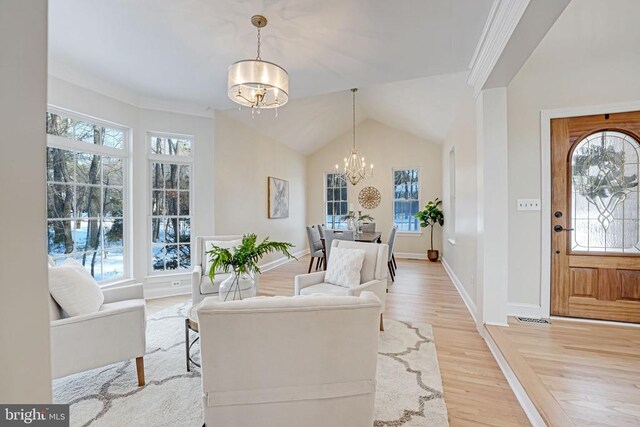 living room featuring an inviting chandelier, light hardwood / wood-style floors, and lofted ceiling