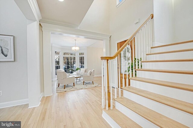 entrance foyer featuring a towering ceiling, light hardwood / wood-style flooring, and ornamental molding