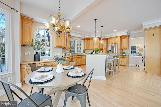 dining room with ornamental molding, sink, an inviting chandelier, and light hardwood / wood-style floors