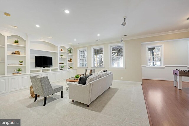 living room with crown molding, light hardwood / wood-style floors, and built in shelves