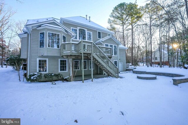 snow covered back of property with a wooden deck