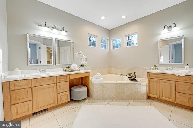 bathroom with tile patterned flooring, vanity, and a relaxing tiled tub