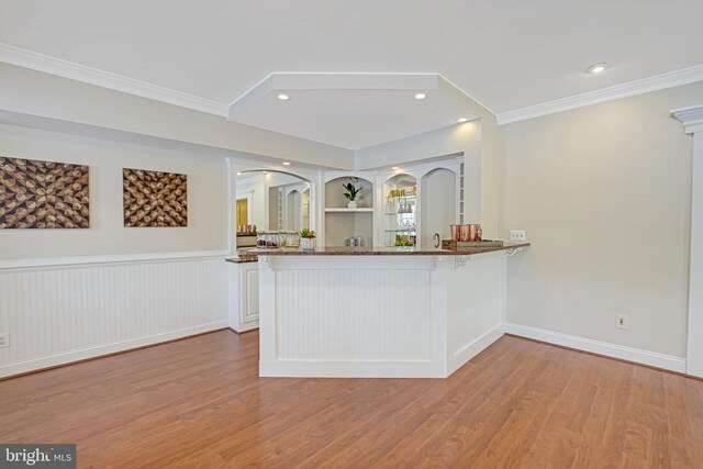 kitchen featuring built in shelves, crown molding, light wood-type flooring, kitchen peninsula, and white cabinets