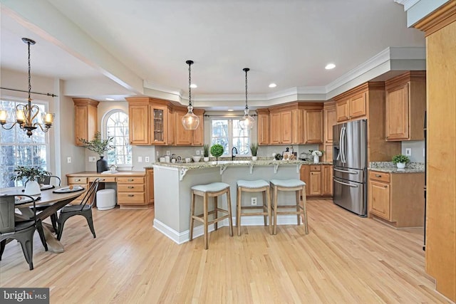 kitchen featuring a kitchen breakfast bar, light stone countertops, stainless steel fridge with ice dispenser, and a kitchen island