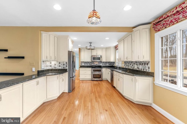 kitchen featuring white cabinetry, hanging light fixtures, backsplash, and appliances with stainless steel finishes