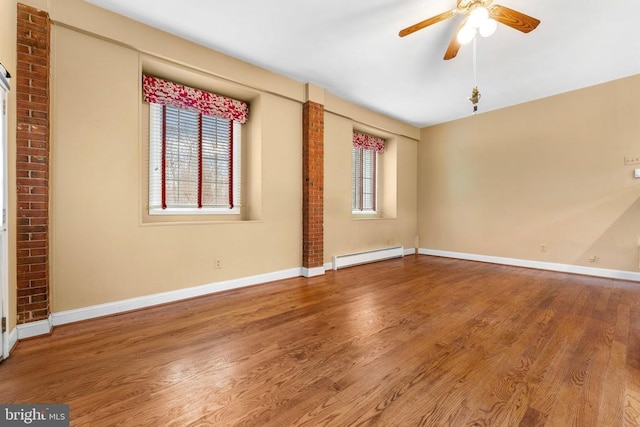 empty room with wood-type flooring, a baseboard heating unit, and ceiling fan