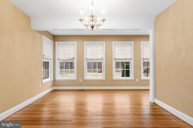 unfurnished dining area featuring an inviting chandelier, hardwood / wood-style floors, and ornamental molding