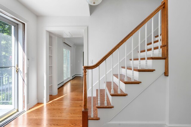 foyer with a baseboard radiator, a healthy amount of sunlight, and hardwood / wood-style floors