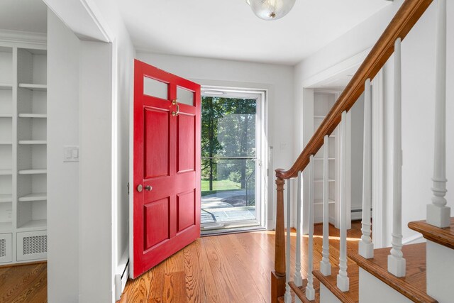 foyer entrance with wood-type flooring and baseboard heating